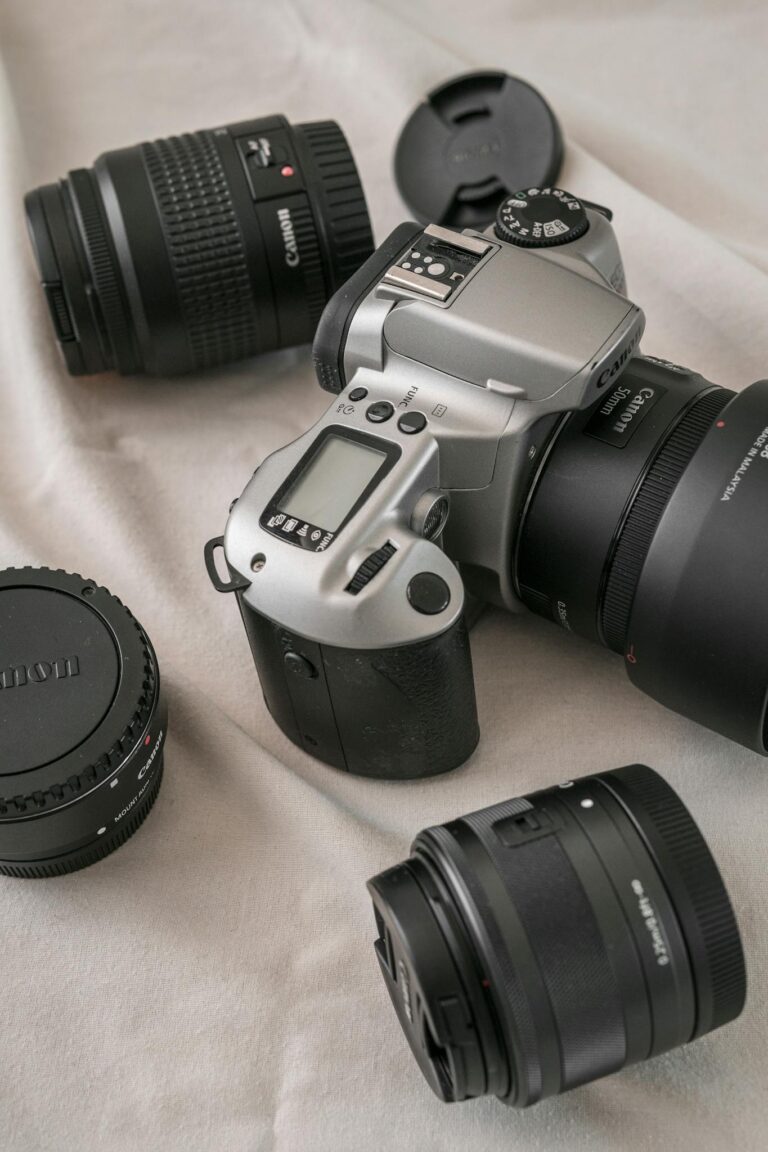 Canon camera with multiple lenses arranged on a beige fabric surface, perfect for tech enthusiasts.