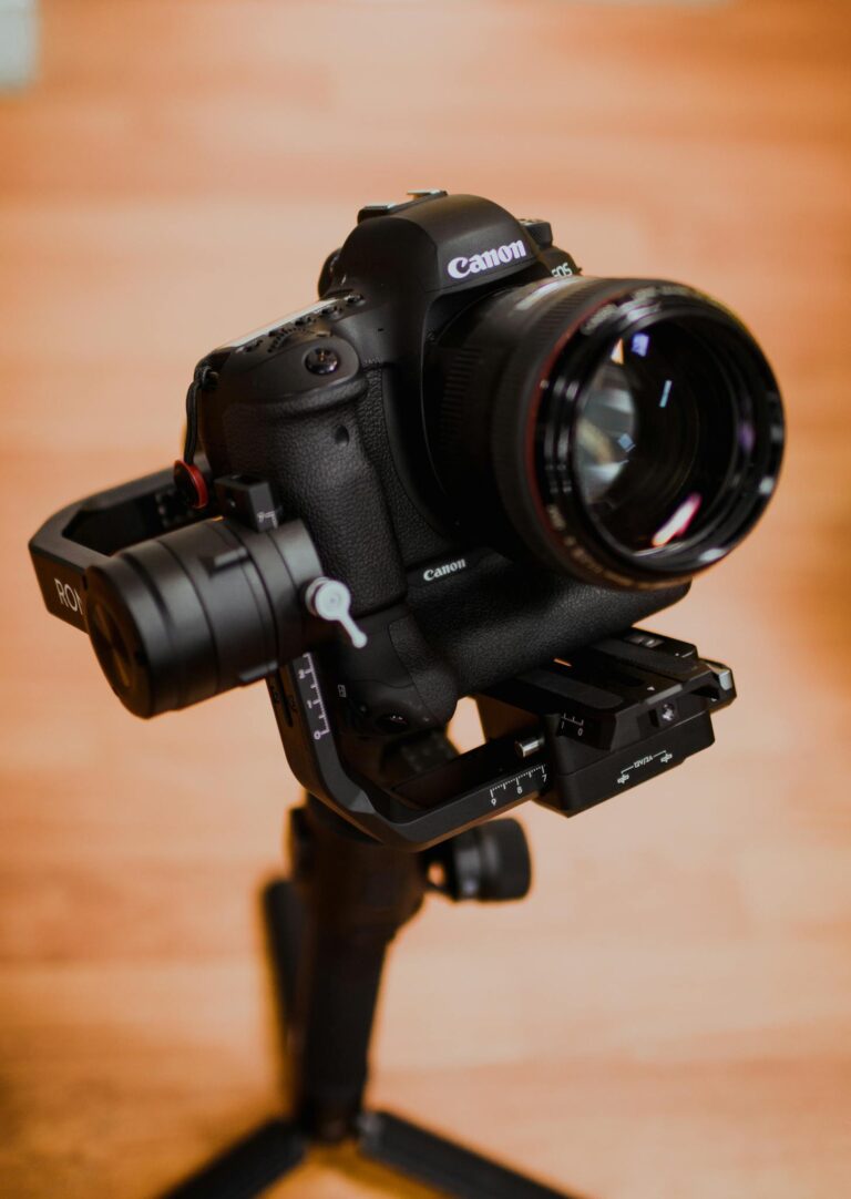 Close-up of a Canon DSLR camera mounted on a gimbal stabilizer indoors.